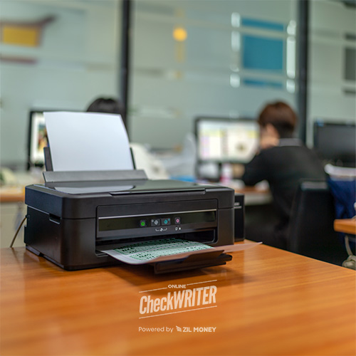 Print Checks Software – Customize And Print On Demand Office Printer Producing a Document Using Print Checks Software, with a Professional Working on a Computer in the Softly Blurred Background