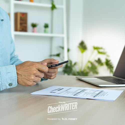 A Person Sitting at a Desk, Bill Pay Online Service, with a Laptop and Decorative Plants in the Background
