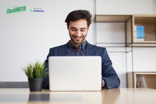 Bulk Payments: Are Gen Z, Millennials & Gen X Businesses Ready for a Revolution in 2025? A Young Man Smiling at His Laptop While Managing Bulk Payment Securely and Quickly for His Business.