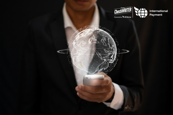 5 International Payments Puzzles Solved in Minutes! Man in a suit holding a phone that projects a digital globe, symbolizing fast, global international payments.