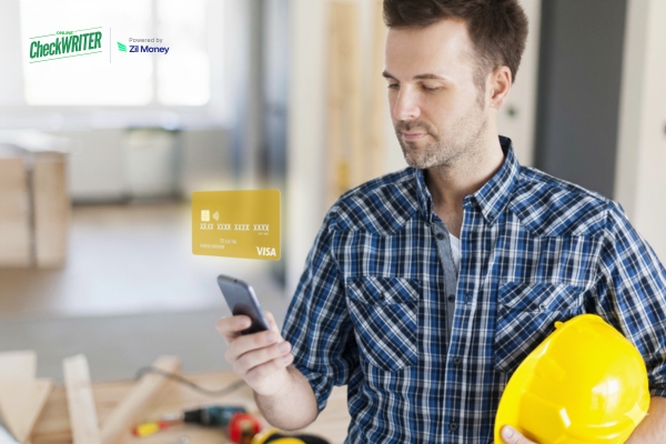 Man in a plaid shirt and hard hat holds a phone with a virtual Construction Worker Card floating above it, showing fast spending control on site.