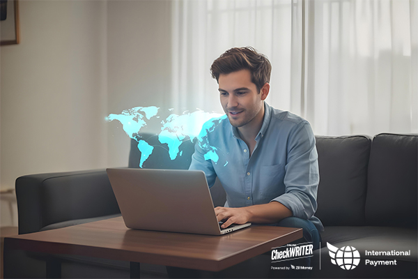 Smiling man on a couch using a laptop with a glowing world map, representing secure and fast international payments.