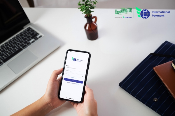 Person signing into a mobile app on a desk, ready to send International Payments quickly and securely from their phone.