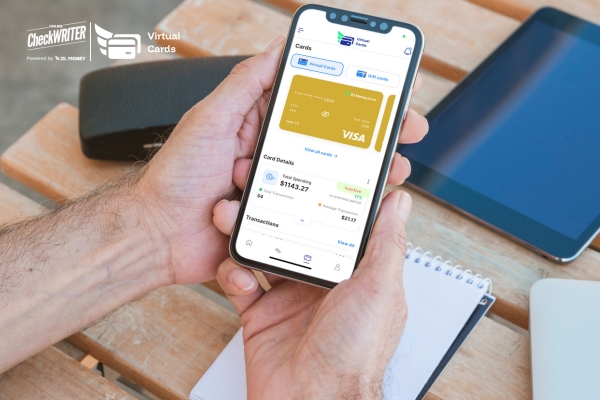 Hands holding a smartphone displaying the mobile app dashboard for a Virtual Card, showing total spending and transaction history outdoors.