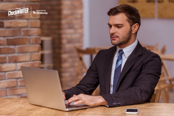 A Businessman Intently Uses a Laptop in a Café, Emphasizing the Efficiency of Seamless Bulk Payment Execution.